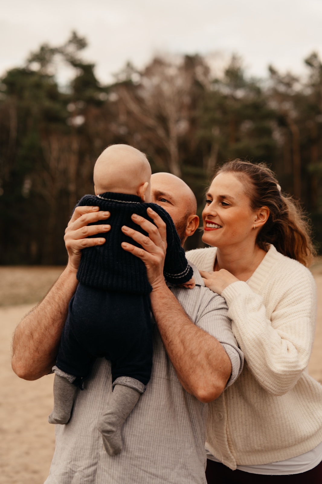 Familienfotos im Sommerlicht – Eltern heben ihr Baby hoch